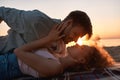 Romantic young couple kissing on the shore with the sun behind them, lying together on the beach at sunset Royalty Free Stock Photo