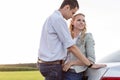 Romantic young couple leaning on back of car at countryside Royalty Free Stock Photo