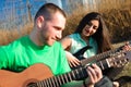 Romantic young couple portrait playing guitar under blue sky Royalty Free Stock Photo