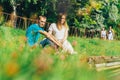 A happy young couple, a guy and a girl sitting on the grass near a river or lake.Romantic young couple sitting on the Royalty Free Stock Photo