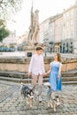 Romantic young couple on a walk in the city with their husky dogs. Beautiful young girl in blue dress and handsome guy Royalty Free Stock Photo