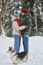 Romantic young couple in winter forest looking at each other and walking dog Royalty Free Stock Photo