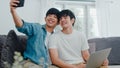 Romantic young gay couple funny selfie by cellphone at home. Asian lover LGBT male happy relax fun using technology mobile phone Royalty Free Stock Photo