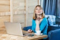 Romantic young girl freelancer with blonde bob haircut hair in blue blouse are sitting alone in cafe and working on laptop and Royalty Free Stock Photo