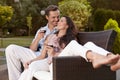Romantic young holding wine glasses on easy chair in park Royalty Free Stock Photo