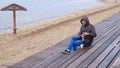 Romantic young man relaxing on the beach with , drinking hot tea or coffee from thermos. Calm and cozy evening. Royalty Free Stock Photo