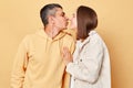 Romantic young man and woman couple standing together isolated over beige background wife and husband hugging and kissing each Royalty Free Stock Photo