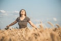 Romantic young woman enjoying nature, raising hands on background of cloudy sky in wheat field, girl breathe breathes deeply, Royalty Free Stock Photo