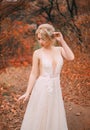 romantic young woman in long white dress posing in fantasy autumn forest. Royalty Free Stock Photo