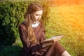 Romantic young woman reading a book in the garden sitting on the grass. Relax outdoor time concept. Royalty Free Stock Photo