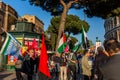 A group of people with flags gathered before at a protest meeting near the Colosseum in Rome.