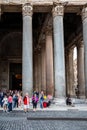 Closeup view of people in front of the famous Pantheon building with tall columns in Rome.