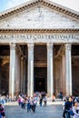 View of people in front of the famous Pantheon building with tall columns in Rome.