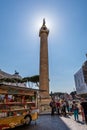 People in front of the famous Trajan`s Column with a food truck in the foreground in Rome.