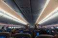 Interior of large passengers airplane with people on seats and stewardess in uniform walking the