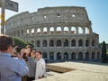 Rome, Italy, 2018. Family takes a selfie in front of the Colosseum in a sunny and warm day of spring