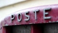 Side perspective view in selective focus of POSTE lettering, on metal roadside container for collecting paper correspondence