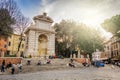 Unrecognizable people sitting on the steps under the monumental marble fountain in the historic Piazza Trilussa in the famous Tras