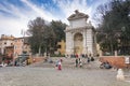 Unrecognizable people sitting on the steps under the monumental marble fountain in the historic Piazza Trilussa in the famous Tras