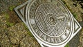 Cast iron manhole cover with Italian writing HYDRAULIC SERVICE, and SPQR of the municipality of Rome, in the morning sun Royalty Free Stock Photo