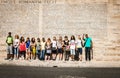 Group of diverse 20\'s turned in street under wall covered with roman text outside Ara Pacis in Rome Royalty Free Stock Photo