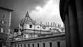 St. Peter`s Square with Bernini`s colonnade on the sides, with Latin inscriptions on the facade and large antique clock on a cloud