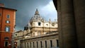 St. Peter`s Square with Bernini`s colonnade on the sides, with Latin inscriptions on the facade and large antique clock on a clo