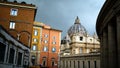 St. Peter`s Square with Bernini`s colonnade on the sides, with Latin inscriptions on the facade and large antique clock on a cloud