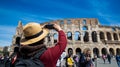 ROME-ITALY-MAY-19-2019:Young man with hat take a picture by smartphone at Colosseum in Rome landmark which Rome Colosseum is one