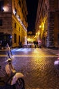 Evening scene in Rome with Vespa bike parked on a paved street