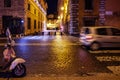 Vespa bike and passing cars in central Rome. Night scene