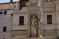 A statue of Saint Anthony is visible in a column with a poor man in his arms.