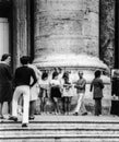 Rome, Italy, 1970 - Three girls in miniskirts rest in the crowd at the foot of a column