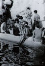 ROME, ITALY, 1970 - A young, blonde female tourist reads a book quietly while refreshing her feet in the Trevi fountain