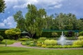 Ron wrought iron gazebo with roof in park with trees and bushes by pond with fountain. Royalty Free Stock Photo