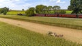 Aerial View of Six Horses Pulling an Amish Harvesting Corn Stalk Machine, as a Steam Passenger Train Travels Bye