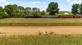 Aerial View of Six Horses Pulling an Amish Harvesting Corn Stalk Machine, as a Steam Passenger Train