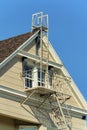 Roof access saftey ladder or fire escape on the tip of house with beige horizontal slatted wood exterior with brown