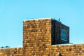 Roof access stairway with wooden exterior pannels and slats with ladde and visible window in clue blue sky background Royalty Free Stock Photo