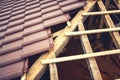 Roof building with ceramic brown tiles on wooden, timber structure. Geometric distribution of roof tiles at house construction