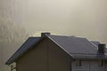 Roof of cottage with siding walls, brown shingle roof and high chimneys in ecological area on foggy landscape copy space Royalty Free Stock Photo