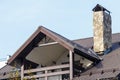 The roof of a country house with a stone chimney and a balcony