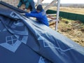 The roof is covered with insulating material, the base of the roof. Worker hammering boards to the base of the roof Royalty Free Stock Photo