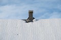 The roof is covered with snow, with a wooden chimney and a blue sky with clouds. Royalty Free Stock Photo