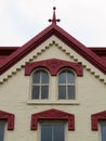 Roof gable with arched windows, painted cream brick, and red trim