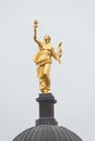 Roof golden statue of ancient beautiful woman with a heart in flame and laurel branch in her hands in historical downtown of