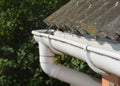 Roof gutter. House asbestos roof with plastic roof gutter pipe. House guttering with holders and old asbestos roof