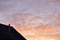 Roof of a house with a chimney on the background of the evening sky with clouds Royalty Free Stock Photo