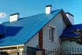 Roof of a house or cottage made of blue metal tiles with drains, slopes, tides, chimney against the blue sky. Metal roof for roof