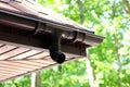 Roof of house with plastic rain gutter on beautiful natural background with green vegetation Royalty Free Stock Photo